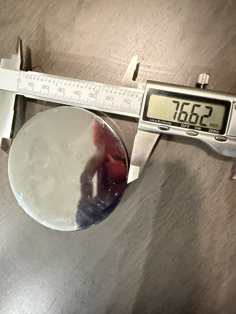 Calipers reading 76.62 millimeters across the wide step of the steel disc